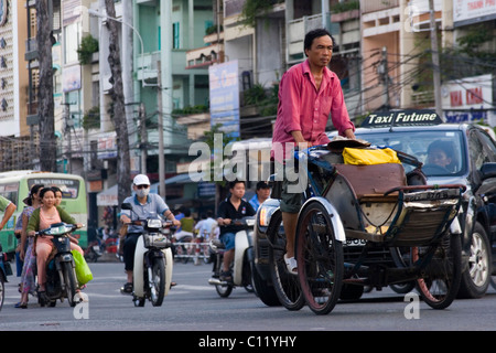 Un cyclo pilote est d'influence sur une rue bondée et occupé avec le trafic lourd à Saigon (Ho Chi Minh Ville) Vietnam. Banque D'Images