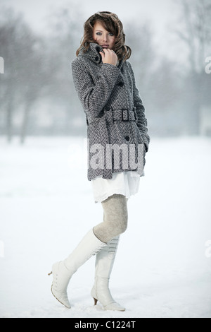 Portrait d'une jeune femme dans la neige, sa main tenant son collier manteau Banque D'Images