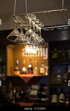 Verres à vin accroché près de comptoir bar avec des bouteilles de vin sur l'arrière-plan Banque D'Images