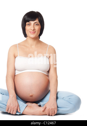 Sitting smiling pregnant woman isolated over white background Banque D'Images