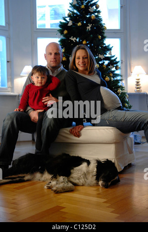 Famille heureuse avec sa fille, père, mère enceinte et de chien, arbre de Noël Banque D'Images