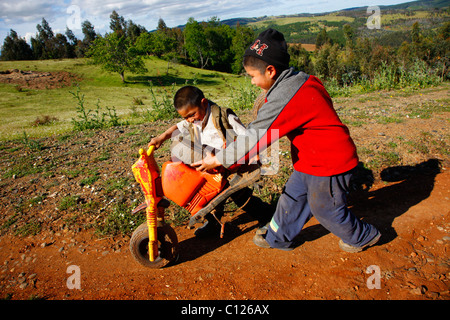 Deux garçons poussant a broken tricycle, Indiens Mapuche, près de Concepción, au sud du Chili, Chili, Amérique du Sud Banque D'Images