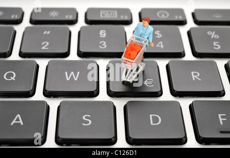 Figure miniature avec panier sur clavier, symbole de l'euro, image symbolique pour le magasinage en ligne Banque D'Images