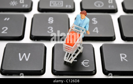 Figure miniature avec panier sur clavier, symbole de l'euro, image symbolique pour le magasinage en ligne Banque D'Images