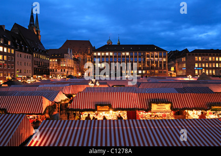 Vue sur le marché de Noël Christkindlesmarkt avec lumières du soir, sur la gauche l'église Sebalduskirche, à l'arrière la ville Banque D'Images