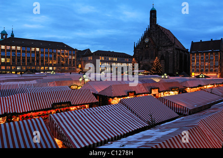 Vue sur le marché de Noël Christkindlesmarkt avec lumières du soir, sur la droite la Frauenkirche église Notre Dame Banque D'Images