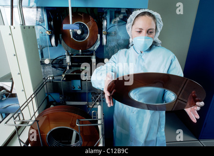 Technicien dans un environnement propre inspecte le revêtement sur un plat, utilisé dans la fabrication de disque dur d'ordinateur, les disques. Banque D'Images