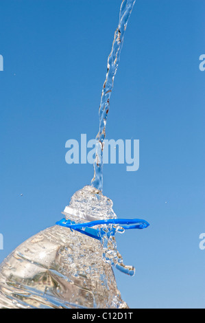 Verser de l'eau dans une bouteille d'eau minérale en plastique contre un ciel bleu Banque D'Images