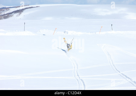 Snowkite équitation dans les montagnes de l'Utah. Suite jaune vif comme il saute au-dessus des montagnes couvertes de neige. Banque D'Images