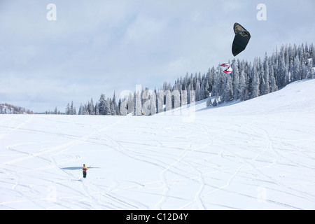 Snowkite équitation dans les montagnes de l'Utah. Voile noir et bleu ciel au-dessus des montagnes couvertes de neige. Banque D'Images