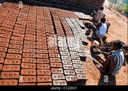 Les hommes indiens maison de briques à la main à l'aide d'un moule et de l'argile humide / boue. Les séchant au soleil avant leur mise à feu fort. L'Andhra Pradesh, Inde Banque D'Images