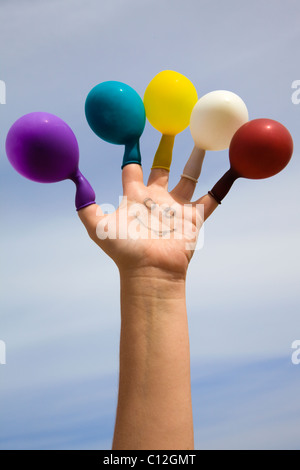 Visage dessiné sur une main avec des ballons de couleur sur les doigts Banque D'Images