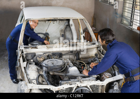 Avec un apprenti mécanicien auto réparation d'une voiture dans un garage Banque D'Images