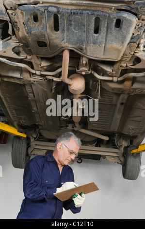 Mécanicien automobile travaillant sous une voiture dans un garage Banque D'Images