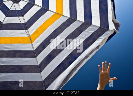 Hand reaching pour parasol à rayures Banque D'Images