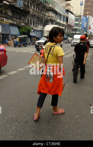 Jeune fille vendre des oiseaux d'être libérés pour faire du mérite, Chinatown , rues de Bangkok, Thaïlande Banque D'Images