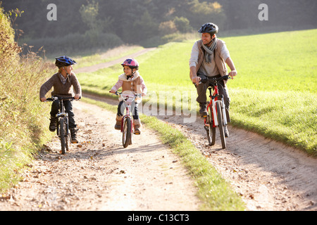 Jeune père avec les enfants faire du vélo dans la région de park Banque D'Images