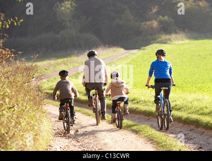 Les jeunes parents avec enfants faire du vélo dans la région de park Banque D'Images