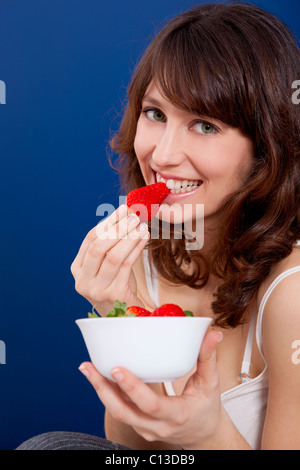 Belle et happy young woman eating strawberries Banque D'Images