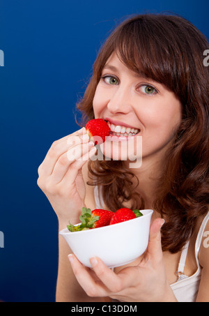 Belle et happy young woman eating strawberries Banque D'Images