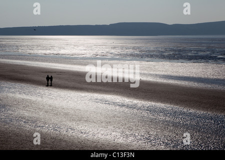 Un couple romantique marche sur Weston Super Mare Beach que le soleil brille dans l'heure d'été Banque D'Images