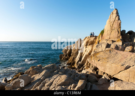 Des gens assis sur des rochers surplombant la baie de Monterey à Pacific Grove, Californie Banque D'Images