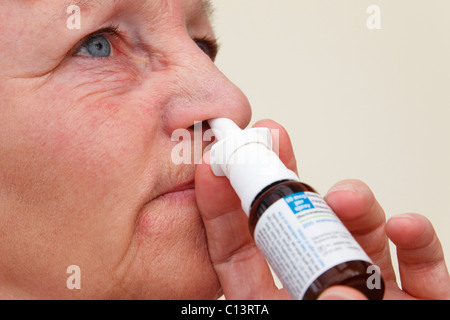 Femme souffrant de la fièvre des foins squirting Beconase Hayfever inhalateur de secours en place une narine de son nez pour soulager des symptômes d'allergie Banque D'Images