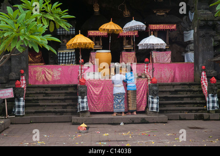 Deux femmes font des offrandes à l'autel dans le temple de la grotte des chauves-souris vieux de 1000 ans appelé Pura Goa Lawah à Klungkung, dans l'est de Bali près de Padang Bai Banque D'Images