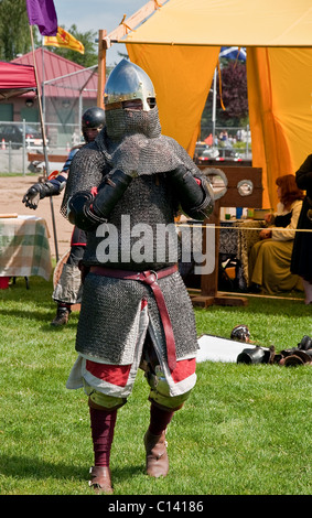 Ce vertical image est un homme habillé comme un chevalier médiéval warrior pour préparer le combat. Un casque de métal brillant, armure de maille. Banque D'Images