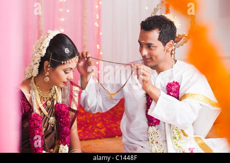 Époux mettant Mangal Sutra pour une mariée à la cérémonie de mariage indien du Sud Banque D'Images