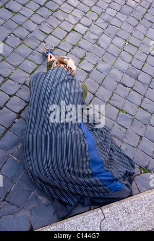 Gypsy femme mendiant gisant sur le pavé de Ponte Sant'Angelo, Rome. Banque D'Images