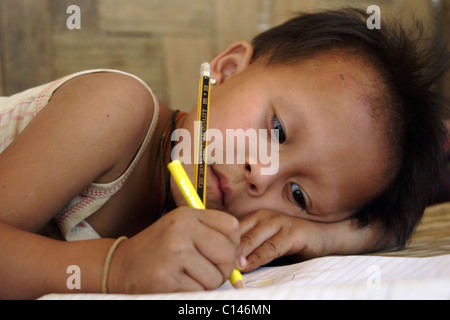 Un jeune 4 ans Karen Paduang jeune garçon réfugié est le dessin dans un livre avec un marqueur jaune à son domicile à Ban Nai Soi, en Thaïlande. Banque D'Images