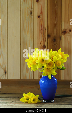 Un bouquet de jonquilles jaune dans un vase bleu sur une surface cuisine en pin. Mars 2010 Banque D'Images