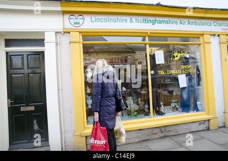 Femme à la recherche de la fenêtre d'un magasin de charité Banque D'Images