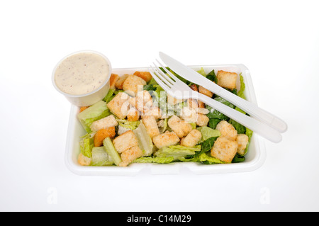 Prêt à manger la salade César avec fromage, croûtons et vinaigrette avec des ustensiles sur fond blanc, découpe. Banque D'Images