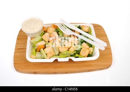 Prêt à manger la salade César avec fromage, croûtons et vinaigrette avec des ustensiles sur fond blanc. Banque D'Images