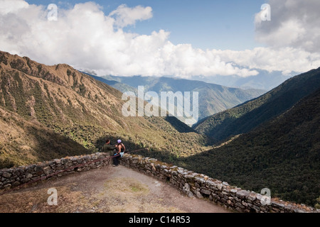 Un jeune couple se distrait à un point d'observation le long du chemin de l'Inca entre les ruines antiques. Banque D'Images