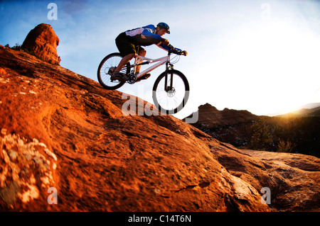 Un homme d'âge moyen chevauche son vtt à travers le red rock country autour de Sedona, Az au coucher du soleil. Banque D'Images