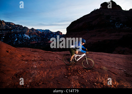 Un homme d'âge moyen chevauche son vtt à travers le red rock country autour de Sedona, Az au coucher du soleil. Banque D'Images