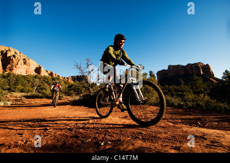 Deux hommes d'âge moyen ride vtt à travers le pays des roches rouges de Sedona, AZ. Banque D'Images