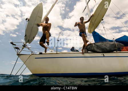 Deux gars sauter leur bateau de partir pour le surf au Costa Rica Banque D'Images