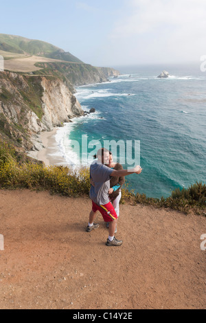 Couple de prendre des photos sur le chemin surplombant les falaises rocheuses/côte de Big Sur, en Californie. Banque D'Images