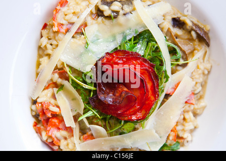 Plat principal aux champignons sauvages, chorizo et tomates séchées 'sun' rizotto surmontée de rocket & parmesan sur plaque blanche 116378 Food10 Banque D'Images