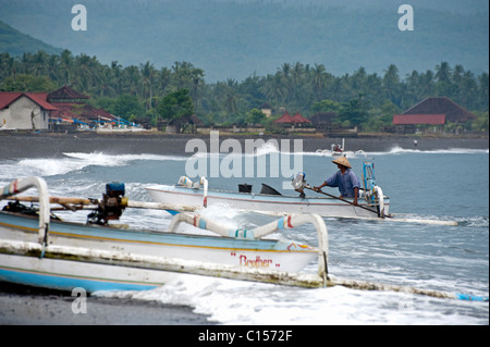 Un pêcheur traditionnel balinais dans un outrigger appelé un jukung retourne à terre après une nuit de la pêche du maquereau. Banque D'Images