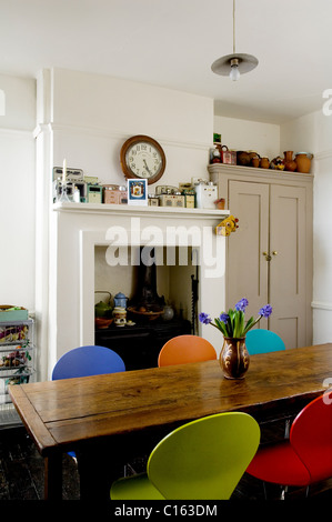 Chaises en bois papillon autour d'une table à manger dans la cuisine avec cheminée et cuisinière Banque D'Images