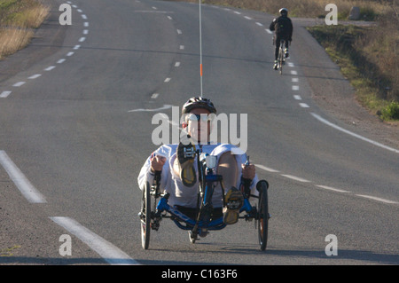 L'homme sur un trike équitation dans tours de route avec un autre cycliste à dos cycliste sur vélo à trois roues Banque D'Images