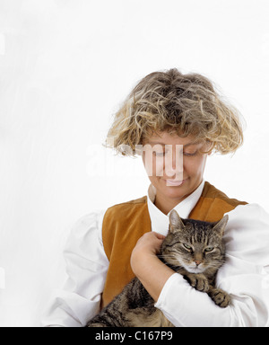 Une femme blonde est maintenant un chat tigré dans ses bras, le chat est le ronronnement de plaisir Banque D'Images