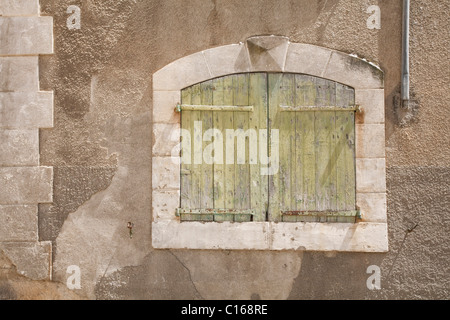 Détail d'un ancien mur de pierre en France avec une fenêtre à volets traditionnels Banque D'Images