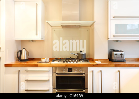 Cuisine moderne avec une cuisinière à gaz, hotte cheminée en bois, plateaux et accessoires en acier inoxydable Banque D'Images