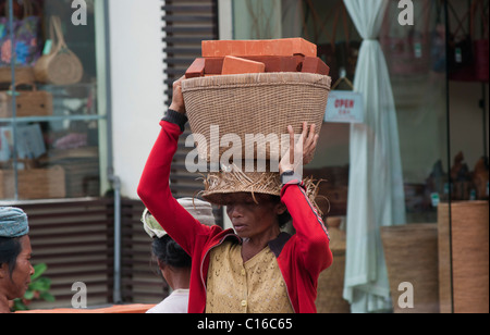 Femme transportant panier de briques sur sa tête à Ubud Bali Banque D'Images